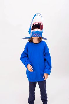 a young child wearing a blue sweatshirt with a shark mask on it's head