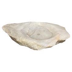 a white rock with a bowl shaped like a shell on it's side, against a white background