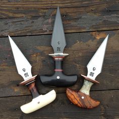 four knives are arranged in the shape of three heads and one knife is on top of a piece of wood