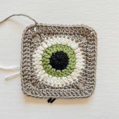 a crocheted square with an eyeball on it is hanging from a string