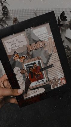 a person holding up a frame with pictures on it