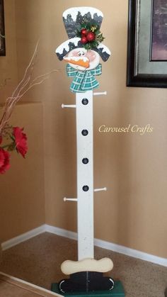 a white and green christmas decoration on top of a wooden stand with flowers in the corner