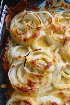 a casserole dish with cheese and onions in it on a blue cloth covered baking pan