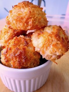 some fried food in a white bowl on a wooden table with chopsticks next to it