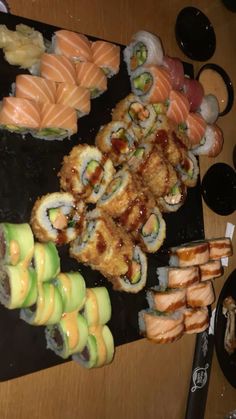 an assortment of sushi on a black platter