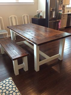 a kitchen table with two benches in front of it and a refrigerator freezer behind it