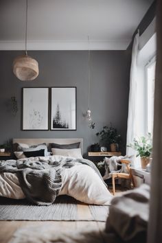 a bedroom with grey walls and white bedding, two framed pictures on the wall