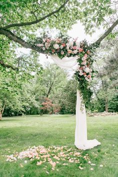 a wedding arch with flowers on it in the grass