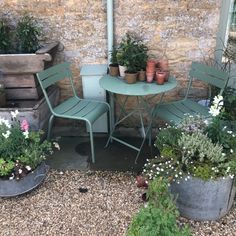 two green chairs sitting next to a table with potted plants on top of it