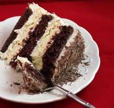 a piece of chocolate cake on a white plate with a fork next to the slice