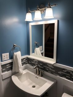 a white sink sitting under a bathroom mirror next to a light above it and a towel hanging on the wall