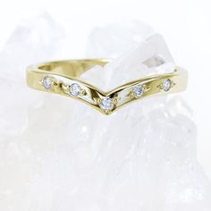 a yellow gold wedding ring with diamonds on top of some ice crystals in the snow