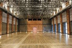 an empty gym with wooden floors and exposed ceilings