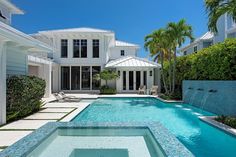 an outdoor swimming pool surrounded by palm trees and white houses with blue tiles on the sides