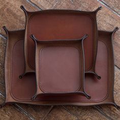 three brown leather trays sitting on top of a wooden floor