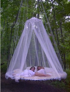 two women laying in a bed with mosquito netting