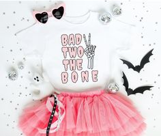 a white shirt with pink tutu skirt and black cat ears on it, next to halloween decorations