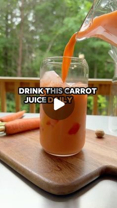 carrot juice being poured into a glass on a cutting board