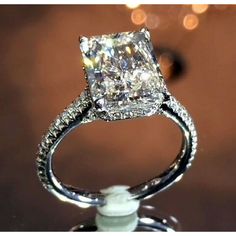 an engagement ring with a princess cut diamond in the center on top of a stand