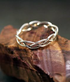 a silver ring sitting on top of a piece of wood