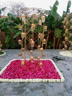 an outdoor area with flowers and candles on the ground, surrounded by greenery in the background