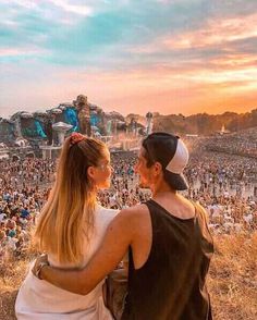 two people sitting on the shoulders of each other at an outdoor concert