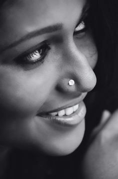 black and white photograph of a woman with piercings on her nose smiling at the camera