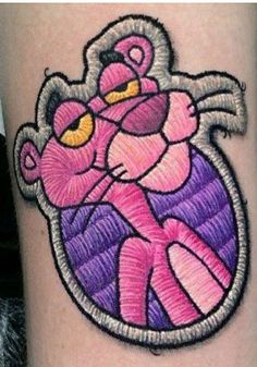 a woman's leg with a pink and purple cartoon character tattoo on the thigh