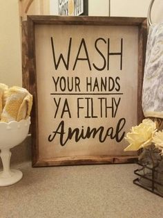 a wooden sign that says wash your hands ya filthy animal next to some towels and flowers