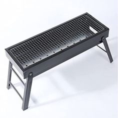 a metal grill sitting on top of a white table next to a black stool with an iron grate