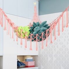 a hanging basket filled with lots of green and yellow balls on top of a shelf