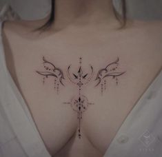 a woman's chest with an artistic tattoo design on her left side ribcage