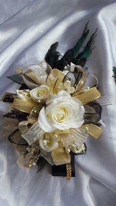 a bridal bouquet with feathers and flowers on a white satin sheeted bed spread