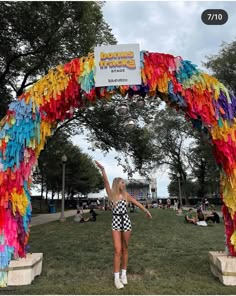 a woman is standing under a colorful arch