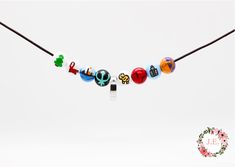 a necklace with different colored beads hanging from a cord on a white background in the shape of letters