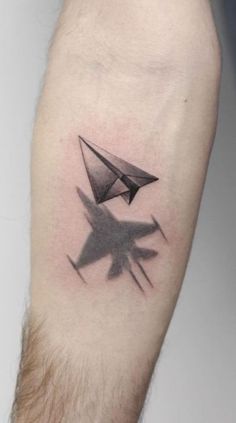 a man's arm with an origami paper airplane tattoo on the left forearm