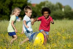 three young children are playing with a frisbee in the grass on a sunny day