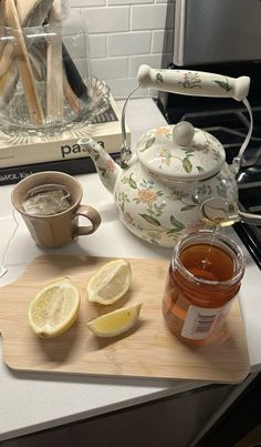 a tea pot and some lemon slices on a counter top with a cup of tea