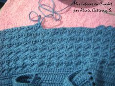 a knitted blue sweater sitting on top of a pink blanket