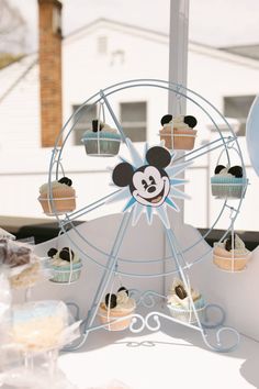 cupcakes are arranged in front of a ferris wheel with mickey mouse on it