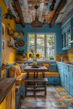 a kitchen with blue and yellow painted walls, wooden ceilinging and an old table in the center