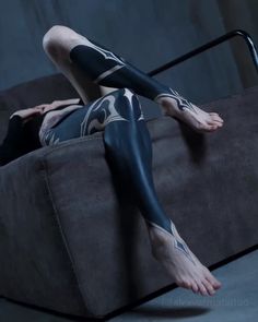 a woman with black and white tattoos laying on a couch