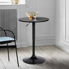 a small table with a bowl on it next to a chair