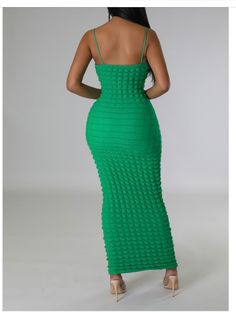 a woman in a green dress with her back turned to the camera and looking down