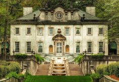 an old mansion with steps leading up to the front door and green grass in front