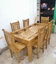 a wooden table and chairs in a room with tile flooring on the ground, next to a green door