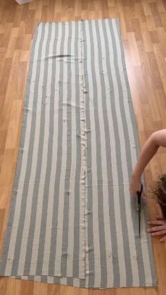 a woman laying on top of a striped rug with scissors in her hand next to a pair of scissors