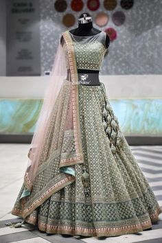 a green lehenga is on display in front of a mannequin's head