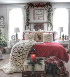 a bedroom decorated for christmas with red and white bedding, plaid throw pillows, evergreen garlands and candles