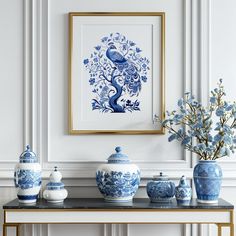 blue and white vases are sitting on a table in front of a framed painting